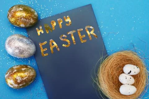Gold and silver Easter eggs with nest on a blue background. Easter concept. H Foto stock