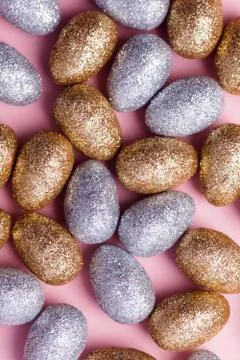 Gold and silver glitter easter eggs on a pastel pink background. Stock Photos
