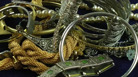 Gold and Silver jewellery rotating on dark blue background Stock Footage
