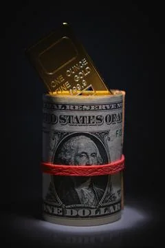Gold bar inserting into dollar bill roll Stock Photos
