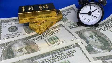 Gold bars and an alarm clock displayed on one-hundred-dollar bills, Stock Photos