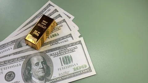 Gold bars placed on multiple US hundred dollar bills, Foto stock