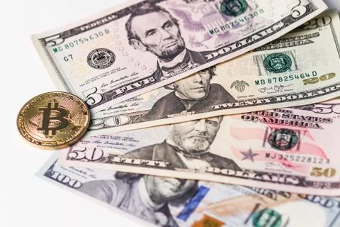 Gold bitcoin on the background of four different banknotes of US dollars. Stock Photos