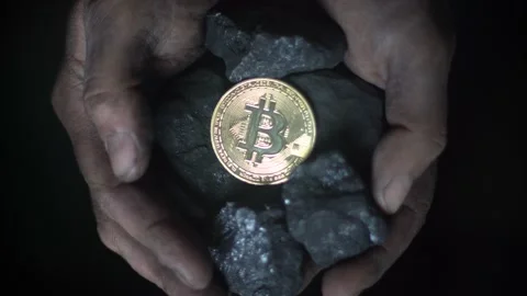 A gold bitcoin coin lies in the hands of a miner. Cryptocurrency miner Stock Footage 239463590