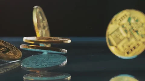 Gold bitcoin coins falling on reflective dark surface in slow motion cinema.. Stock Footage 337447871