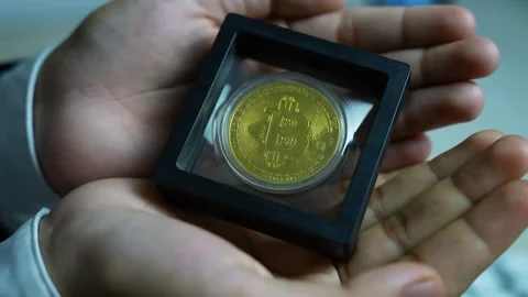 Gold bitcoin in display case, Hands holding a framed gold bitcoin coin in p.. Stock-Footage 329176969