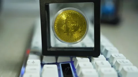 Gold bitcoin on keyboard in display frame, Gold bitcoin coin displayed in a.. Видео 329176984