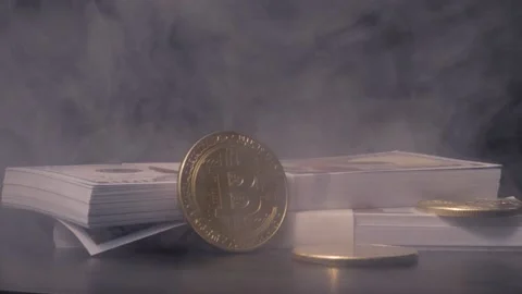 Gold Bitcoin leaning on stacks of one hundred dollar bills with light Stock Footage 217947247