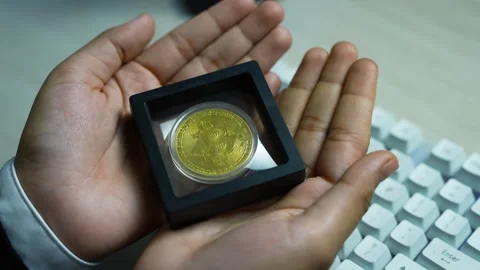 Gold bitcoin in protective frame, Hands holding a framed gold bitcoin coin .. Видео 329176990