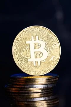 A Gold bitcoin on a stack of coins. Stock Photos