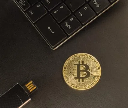Gold bitcoin on the table next to the keyboard and USB flash drive Stock Photos
