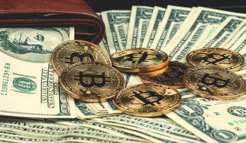 Gold bitcoin, on top of dollar stack. Stock Photos