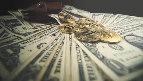Gold bitcoin, on top of dollar stack. Stock Photos
