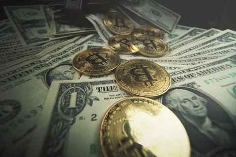 Gold bitcoin, on top of dollar stack. Stock Photos