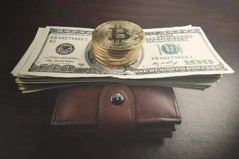 Gold bitcoin, on top of dollar stack. Stock Photos