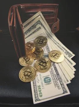 Gold bitcoin, on top of dollar stack. Stock Photos