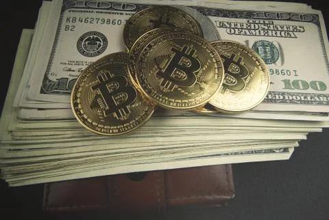 Gold bitcoin, on top of dollar stack. Stock Photos