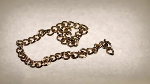 A gold chain falls onto a white surface Stock Footage 303300116