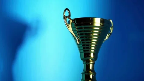 Gold champion trophy cup standing on vibrant blue background Stock-Footage 333810672
