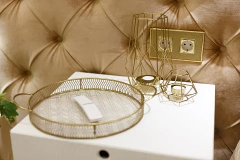 Gold-colored decorative elements lie on a white nightstand. Stock Photos