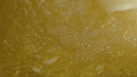 Gold-colored liquid with gold flakes spills into a container Stock Footage 291870817