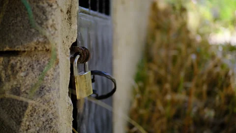 Gold-colored padlock hangs on old vintage door in middle of stone walls. locked Stock Footage 165907369