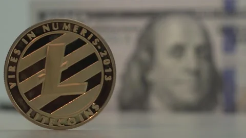 Gold cryptocoin Litecoin on white table. !00 USD bank note on the background Stock Footage 142315664