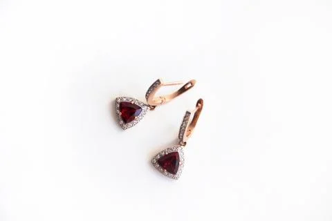 Gold earrings with red precious stone and small diamonds on a white backgroun Stock Photos