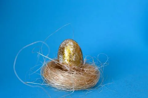 Gold Easter egg on a blue background in the nest close. Easter concept. Happy Фото