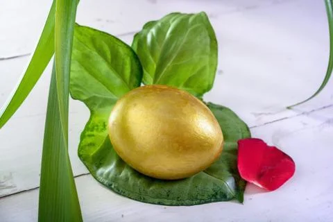 Gold easter eggs among green leaves Stock Photos