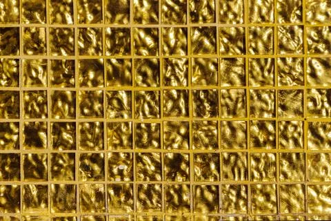 Gold embossed background, square cells. Small golden tile on the wall. Stock Photos