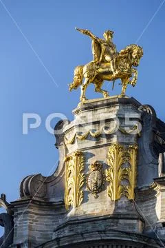 Gold equestrian statue on top of building with decorative gold trim and blue sky Stock Photos