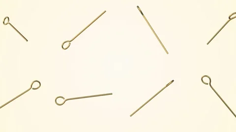 Gold Eye Head Pins Falling on a Light Background. Earring Accessories 3D. 4K Stock Footage 304515109