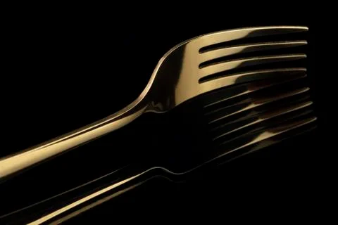 Gold fork on a black background with reflection. Cutlery. Stock Photos