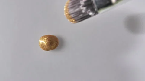 Gold gel fluid with flowing down on a white surface. Molten gold. Sparkling Stock Footage 143530255
