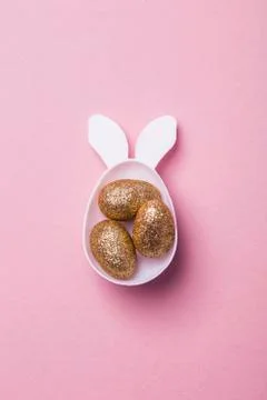 Gold glitter eggs in a white easter bunny egg shape with ears Stock Photos