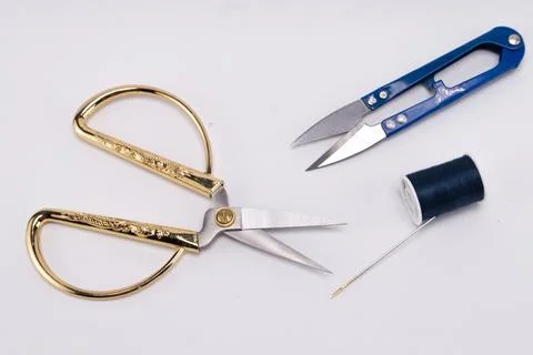 Gold-handled scissors, blue thread snips, and a spool of navy thread with n.. Stock Photos