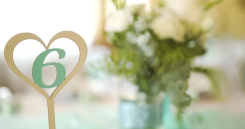 Gold heart table marker with green six in bright event setting Stock Footage 336469608