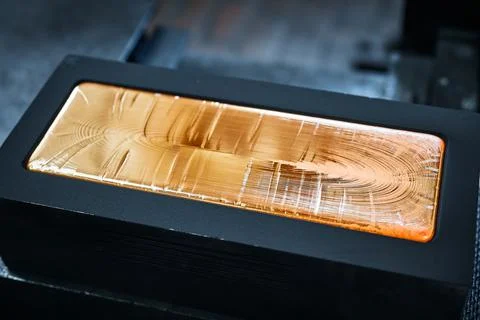 Gold ingot in graphite casting form on workbench at plant Stock Photos