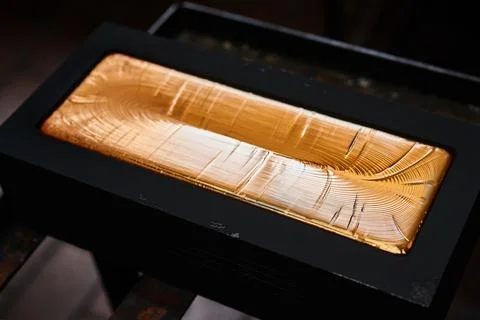 Gold ingot in graphite casting form on workbench at plant Stock Photos