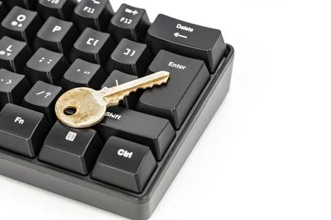 Gold key resting on enter key of black computer keyboard, security concept Stock Photos