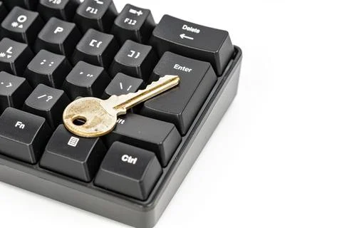 Gold key resting on enter key of black computer keyboard, security concept Stock Photos