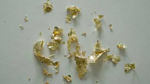 Gold leaf shimmering under moving light on a textured studio carpet Stock Footage 291870871