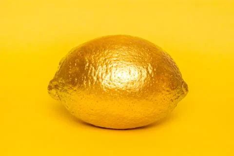 Gold lemon on yellow background. Creative concept with fruit. Stock Illustration