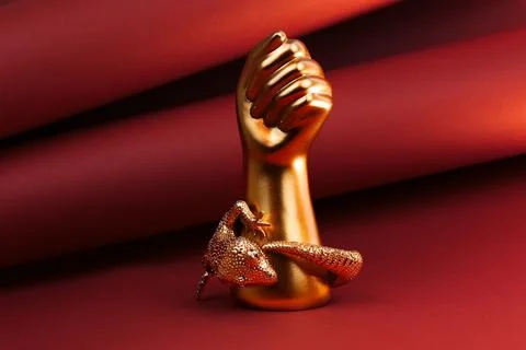 Gold lizard cuff bracelet displayed on a sculptural gold hand Stock Photos