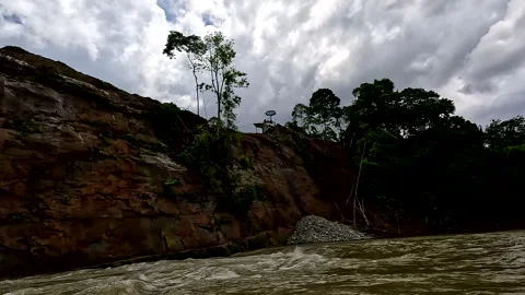 Gold mining activities: people are dumping the dirt down a cliff showing Stockbeeldmateriaal 336917150