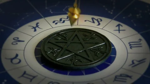 A gold pendulum swinging on astrological chart with pentacle in the center Stock Footage 1062059