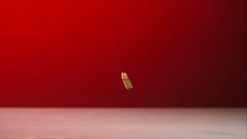 Gold rifle bullets fall and bounce onto a surface against red light. Stock Footage 326626085