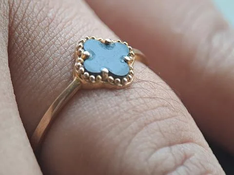 Gold ring with a blue gemstone set in a beaded bezel, worn on a finger indo.. Stock Photos