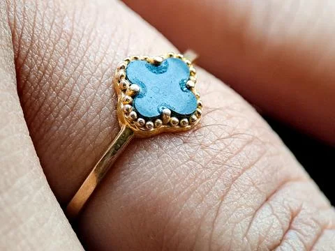 Gold ring with a blue gemstone set in a beaded bezel, worn on a finger indo.. Stock Photos